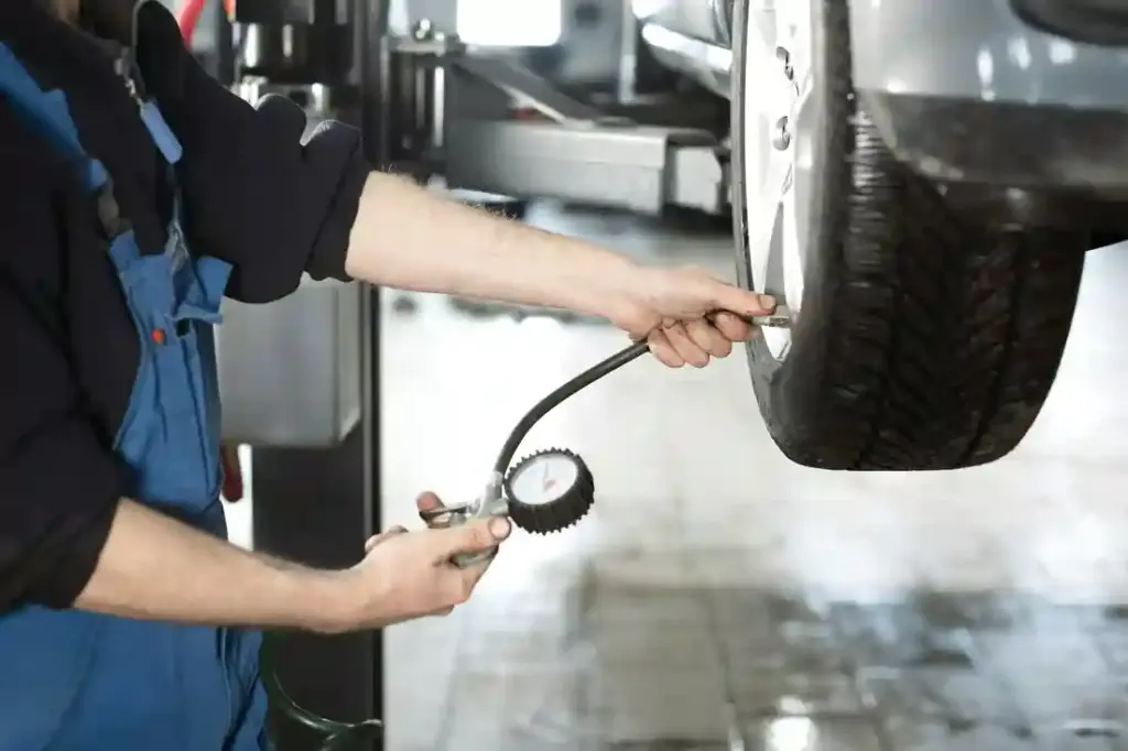 Mechanic checking tire pressure at the wheel