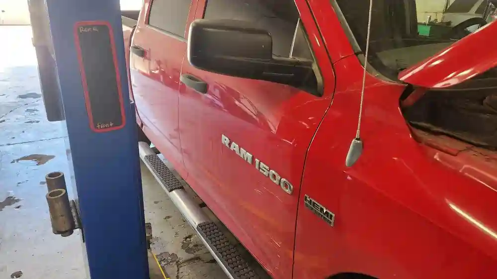 Red Dodge Ram 1500 on a lift at T Autocare Takedown in Broken Arrow with the hood open for a pre-purchase inspection