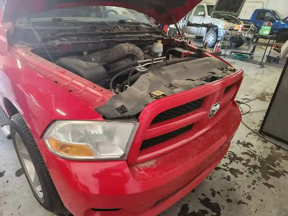 Close-up of the engine bay of a 2012 Dodge Ram 1500 with the hood open during an inspection at T Autocare Takedown in Broken Arrow